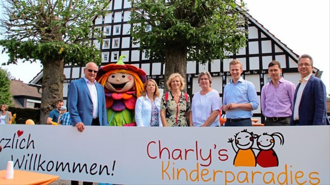 Gruppenfoto vor einem Charly's Kinderparadies Herzlich Willkommen Banner