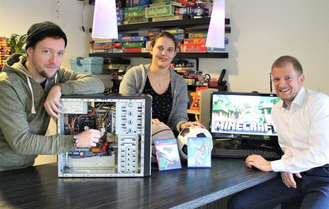 Gruppenfoto der Jugendhilfe - Sie präsentieren einen Rechner, Fußbälle, PlayStation Spiele und Minecraft