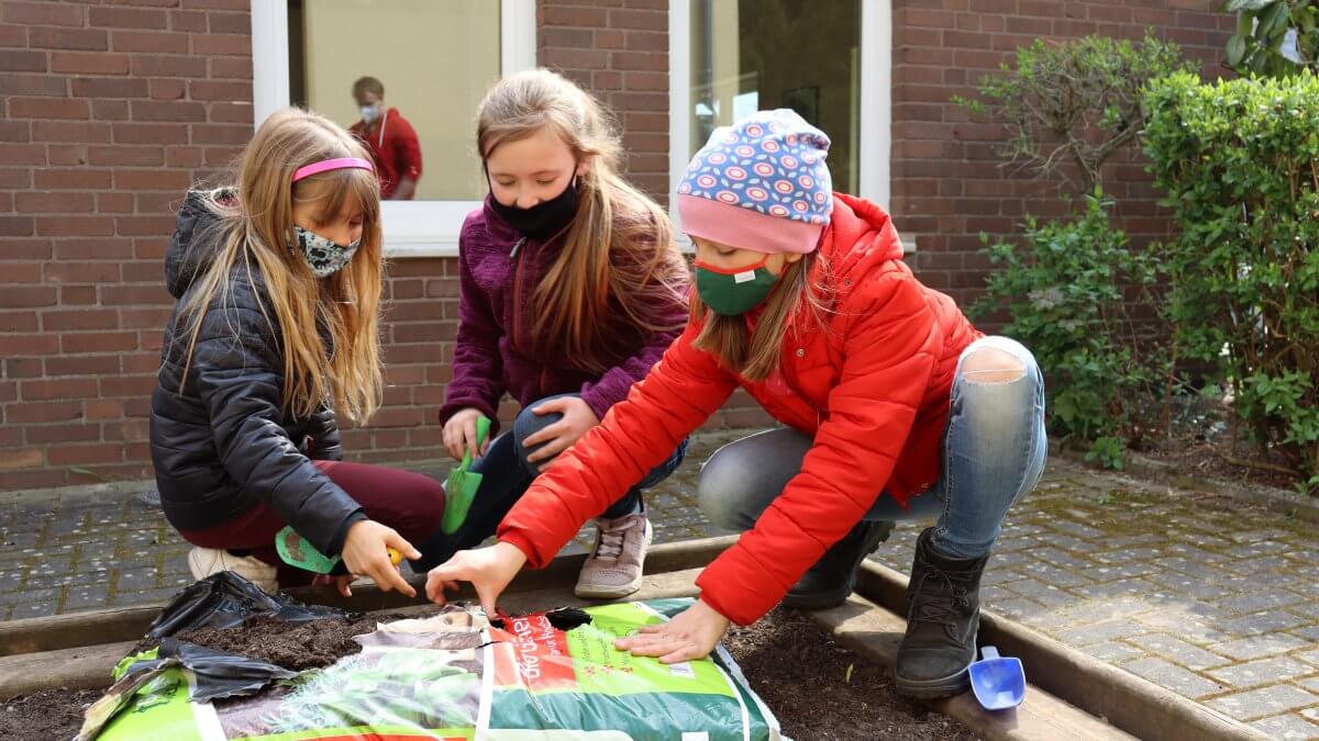 Schüler öffnen einen Sack Gärtner-Erde